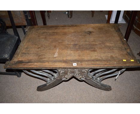 An Eastern style stained and carved hardwood rectangular occasional table, with carved decorated sides and splayed legs suppo