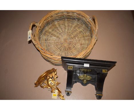 An ebonised wall bracket; together with a gilt decorated wall bracket; and a wicker basket.