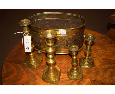 An oval brass shaped planter with floral decoration; together with a pair of brass candlesticks; and another pair of candlest
