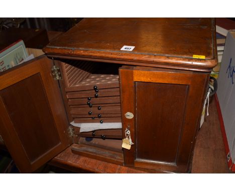 A mahogany table coin cabinet, fitted two panelled doors opening to reveal a fitted interior of drawers with two inset brass 