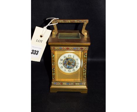 A brass, enamel and glass carriage clock with enamel decoration, circular arabic dial with enamelled centre panel.