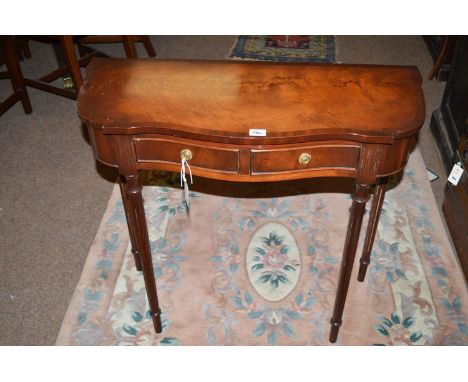 A reproduction mahogany side/hall table with crossbanded shaped top, fitted two shallow drawers to the frieze, raised on slen