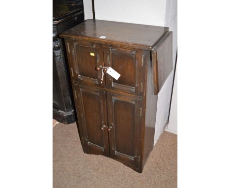 A stained oak tall narrow hall cupboard, fitted a single fall-flap to the right-hand side, the cupboard in the top with two p