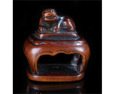 Japanese Edo period netsuke, carved as a Shishi above a table, 3.2cm wide