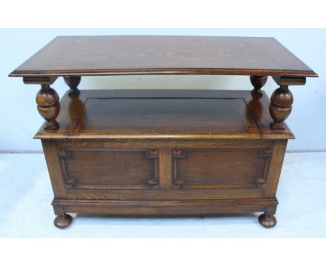 A 20th Century stained oak monks bench, with hinged seat enclosing storage compartment, above a panelled front and raised on 