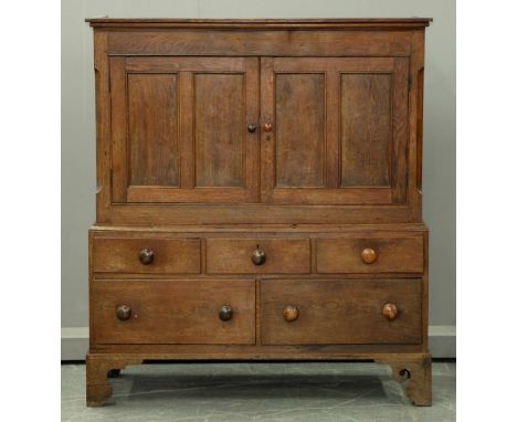 A George III oak press cupboard, with moulded frieze above pair of panelled doors enclosing shelf, the lower part fitted with