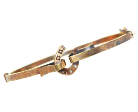 A gold bangle, early 20th c, centred by a horseshoe set with split pearls, 57mm (internal), marked 585, 6.8g Good condition