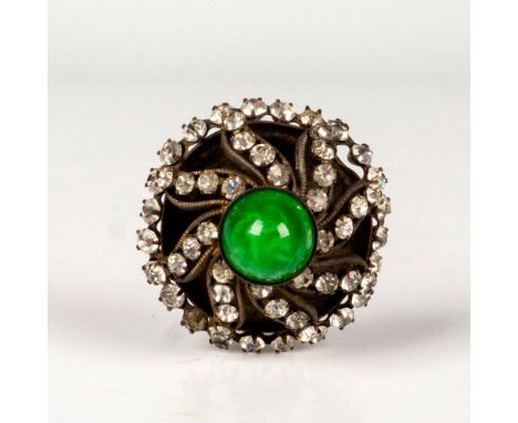 Shimmering pin decoration with rhinestones that surround a small green stone in center atop a silver-tone metal head. Dimensi