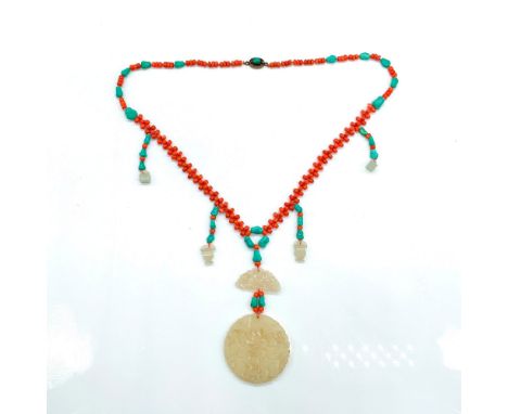 Turquoise and coral tone beads with carved jade accents and pendant that measures 2.25"dia. Necklace has a filigree clasp and