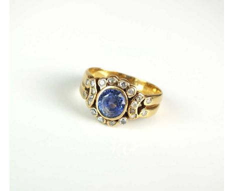 A sapphire &amp; diamond cluster ring, designed as a central oval mixed cut sapphire collet set in yellow metal within a surr