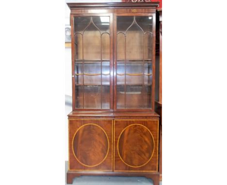 Late George III style mahogany bookcase, the moulded cornice with boxwood and ebony oval radiating inlay over a pair of glaze
