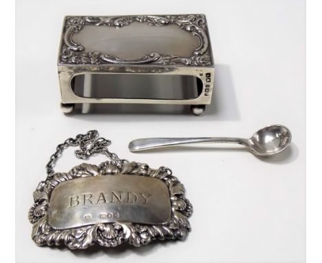 Silver foliate scroll embossed matchbox holder; together with a 'BRANDY' spirit label and a silver mustard spoon, weight 1.30