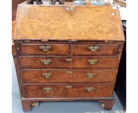 George III burr walnut feather banded bureau, the fall front enclosing a hinged door and six drawers and six pigeonholes, the