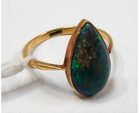 Good yellow metal black opal set ring, the pear shaped polished stone displaying green, blue, orange and red and of 3ct sprea