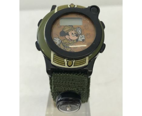 A Mickey Mouse " Safari Adventures " digital watch with green woven fabric strap. Compass to strap and magnifier to front of 