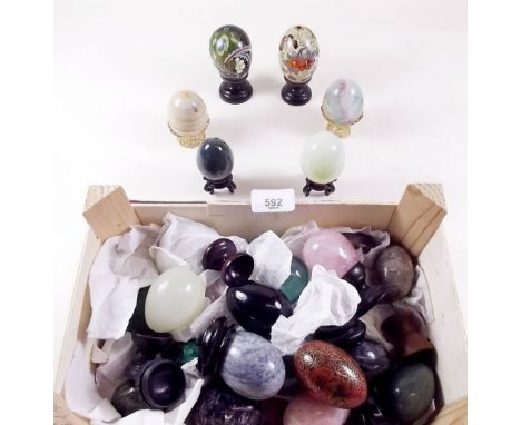 A collection of specimen stone eggs including malachite, rose quartz, amethyst and two cloissonne eggs and various stands 