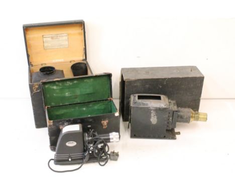 Two magic lantern slide projectors together with a later electric example, all complete with storage cases. (A/F). 