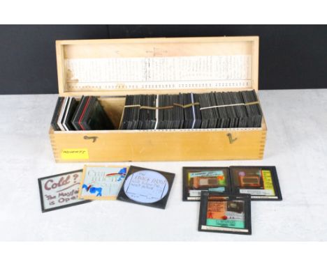 A collection of approx 50 glass magic lantern slides contained within a wooden case to include advertising and movie posters.