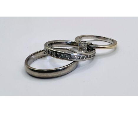 A bridal suite of three rings: a plain palladium band ring; a half eternity ring set with 21 princess cut diamonds (estimated