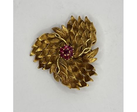 AN 18k stylized floral brooch with ruby cluster to the centre, stamped 750, CFF. Approx gross weight 19.6 grams.