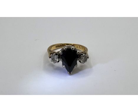 An 18ct gold dress ring set with a pear shaped dark blue sapphire, measuring approx 9mm x 7mm x 4mm, and two round brilliant 