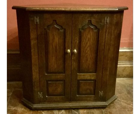 A George III style oak floor corner cupboard, triangular form moulded top and base, a panel door opens to a single shelf over