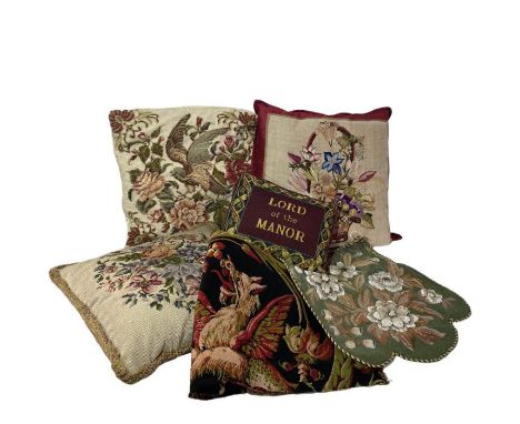 Three needlework cushions and one with an embroidered front, a piece of antique German tapestry style upholstery fabric, a ne