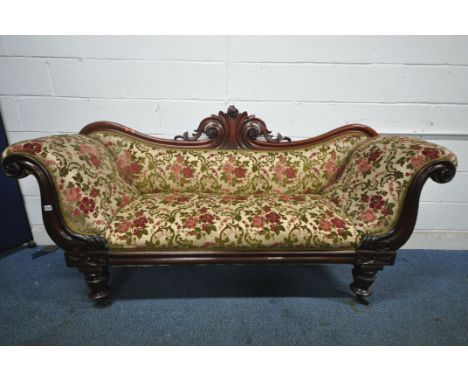 A VICTORIAN MAHOGANY SOFA, with scrolled armrests, wavy back and foliate carved centre, on octagonal legs and castors, length