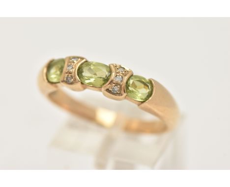 A 9CT GOLD PERIDOT AND DIAMOND DRESS RING, set with three oval cut peridots with single cut diamond accents, to a polished ba