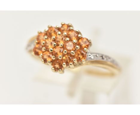 A 9CT GOLD CITRINE AND DIAMOND RING, designed as a cluster of circular cut Citrine, cross over shoulders with small diamond a