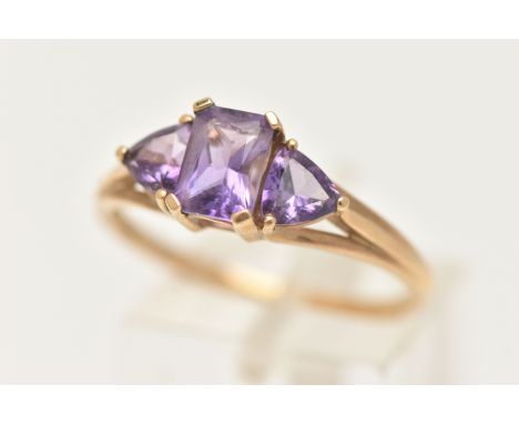A 9CT GOLD AMETHYST RING, set with a central rectangular cut amethyst in a four claw setting, flanked with two triangular cut