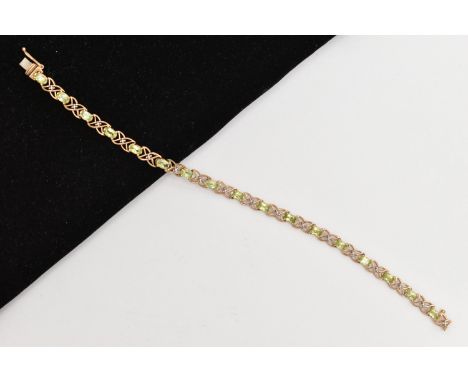 A 9CT GOLD PERIDOT LINE BRACELET, designed as a series of seventeen oval cut peridots, each in a four claw setting, interspac