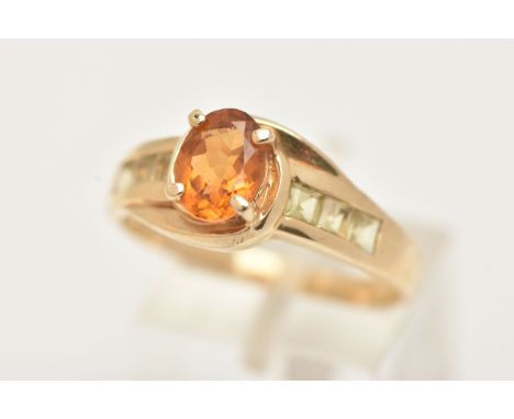 A 9CT GOLD CITRINE RING, set with a central oval cut Citrine, in a four claw setting, cross over shoulders set with lighter s