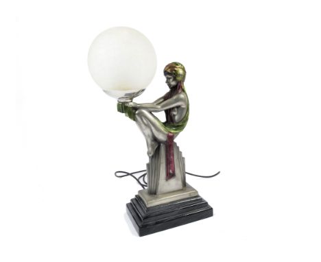 An Art Deco style figural lamp, modelled as a woman holding a crystal ball, the glass shade the crystal ball, on a stepped ma