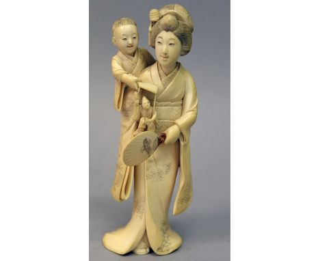 A SIGNED JAPANESE MEIJI PERIOD IVORY OKIMONO OF A BIJIN, standing and holding a fan, her son on her shoulder dangling a puppe