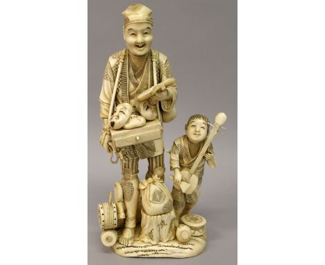 A LARGE JAPANESE MEIJI PERIOD IVORY SECTIONAL OKIMONO OF A MASK SELLER, in the company of his son who bears a stringed samise