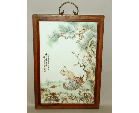 A CHINESE WOOD FRAMED FAMILLE ROSE RECTANGULAR PORCELAIN PLAQUE, decorated with calligraphy and with a seated sage leaning fo