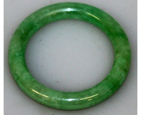 A GOOD QUALITY GREEN JADE BANGLE, with paler inclusions, 2.9in diameter, the inner rim 2.1in diameter.