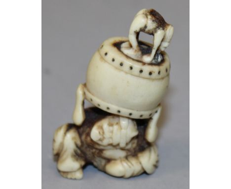 A JAPANESE MEIJI PERIOD STAGHORN NETSUKE, carved in the form of an oni bearing the weight of a temple bell, 2.2in high.