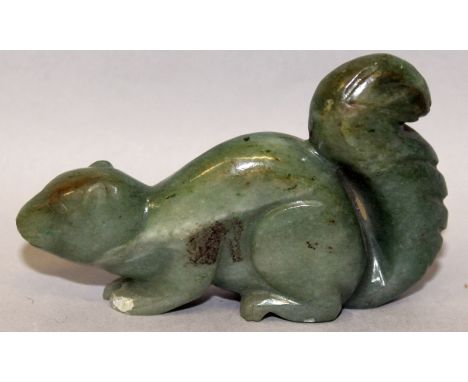 A 20TH CENTURY CHINESE GREEN JADE-LIKE CARVING OF A SQUIRREL, the stone with lighter inclusions and striations, 3.1in long.