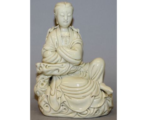 A CHINESE BLANC-DE-CHINE PORCELAIN FIGURE OF GUANYIN, leaning on a cloud scroll plinth, the reverse with impressed marks, 5.3