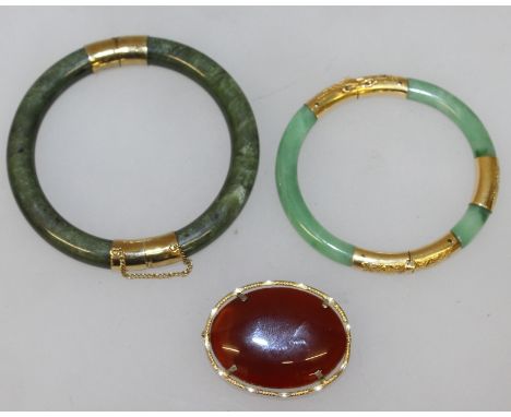 TWO 20TH CENTURY CHINESE GILT-METAL MOUNTED JADE BANGLES, 3.25in & 2.8in diameter, the inner rims 2.4in. & 2.2in diameter; to