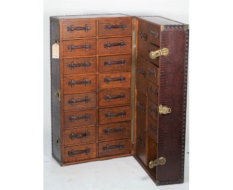 A modern faux crocodile skin upholstered upright travelling trunk fitted with thirty-two short drawers, 46cm wide x 118cm hig
