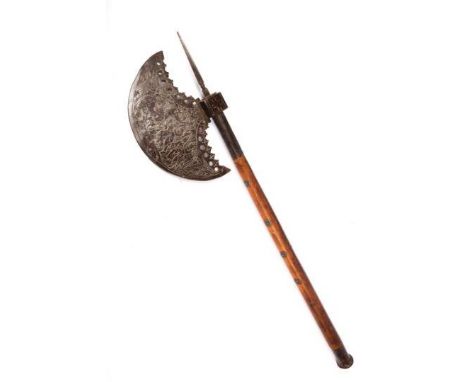 An Indian axe, the crescent head chiselled with an elephant and figures being executed, on its 25" wooden haft studded with b