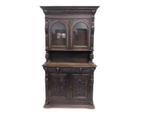 A late 19thC Flemish style ebonised oak cabinet, the top with a moulded cornice above gadrooned frieze, two arched glazed doo