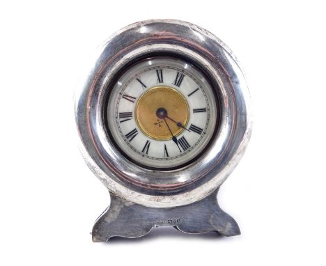 An Edwardian silver cased easel backed clock, the white enamelled dial with Roman numerals, with plain circular cushioned fra