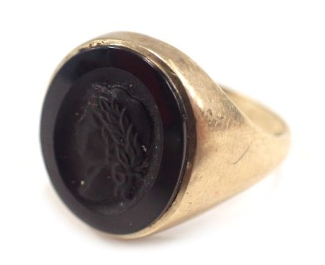 A 9ct gold signet ring, set with carved jet Grecian figure, in a rub over border, hallmarks rubbed, ring size V, 5.4g all in.