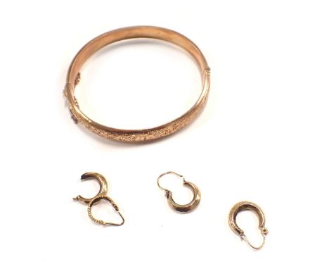 A George V 9ct rose gold hinged bangle, of half hoop design, with floral scroll decoration and safety chain, Chester 1913, an