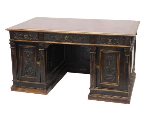 A Continental carved oak pedestal desk, the rectangular top with an ox blood red leatherette inset, with a moulded edge above