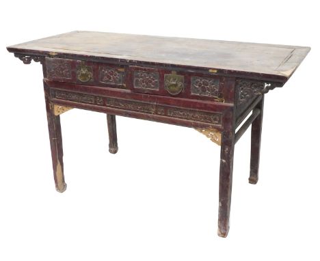 A Chinese red stained altar table, of planked top, with two carved frieze drawers with brass handles, flanked by pierced brac